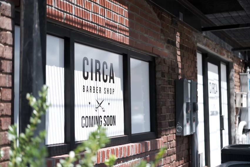 sign on the window of a brick and mortar building indicating that circe barbershop is coming soon.